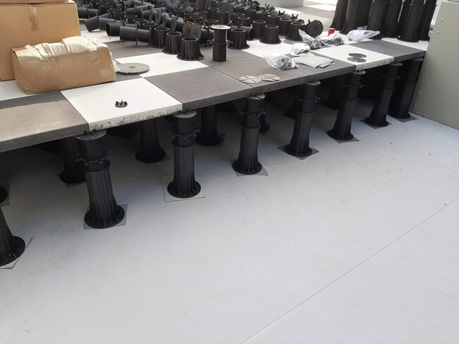 Raised floor system installation featuring adjustable pedestal supports under outdoor paving tiles.