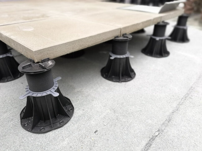 Adjustable pedestal pavers system supporting outdoor concrete tiles during installation.