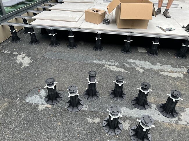 Adjustable deck pedestals lined up on a surface during terrace tile installation.