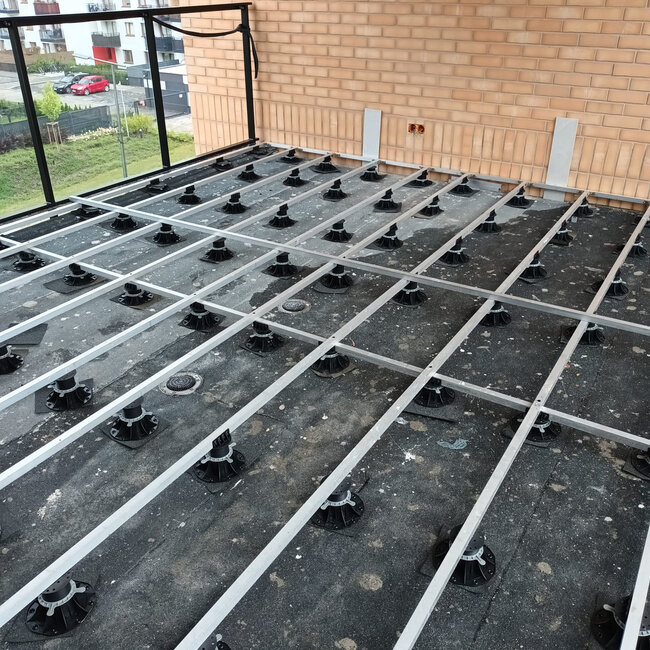 Aluminum joist grid substructure supported by adjustable pedestals on a rooftop terrace.