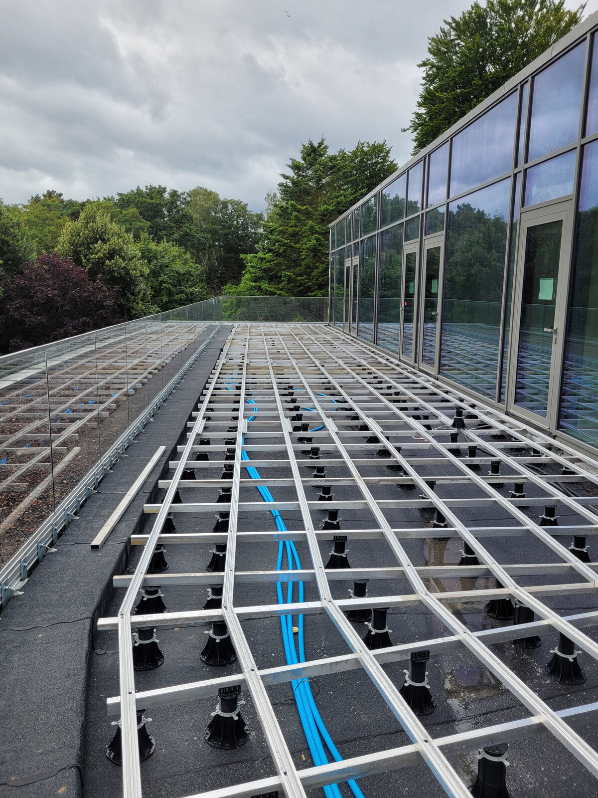 Aluminum joist framework mounted on adjustable plastic pedestals for outdoor terrace flooring.