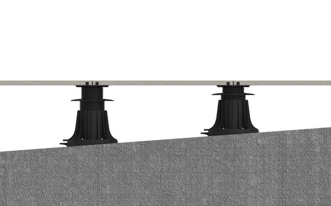 Adjustable plastic pedestal supports leveling pavers on a sloped concrete surface.