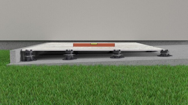 Levelling patio tile on adjustable pedestals with a spirit level.