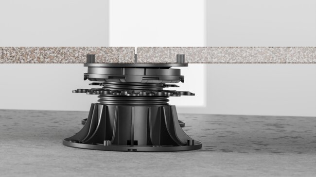 Side profile of stone paver tiles supported by an adjustable plastic pedestal riser.