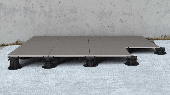 Grid of outdoor paver tiles installed on adjustable plastic pedestal risers.