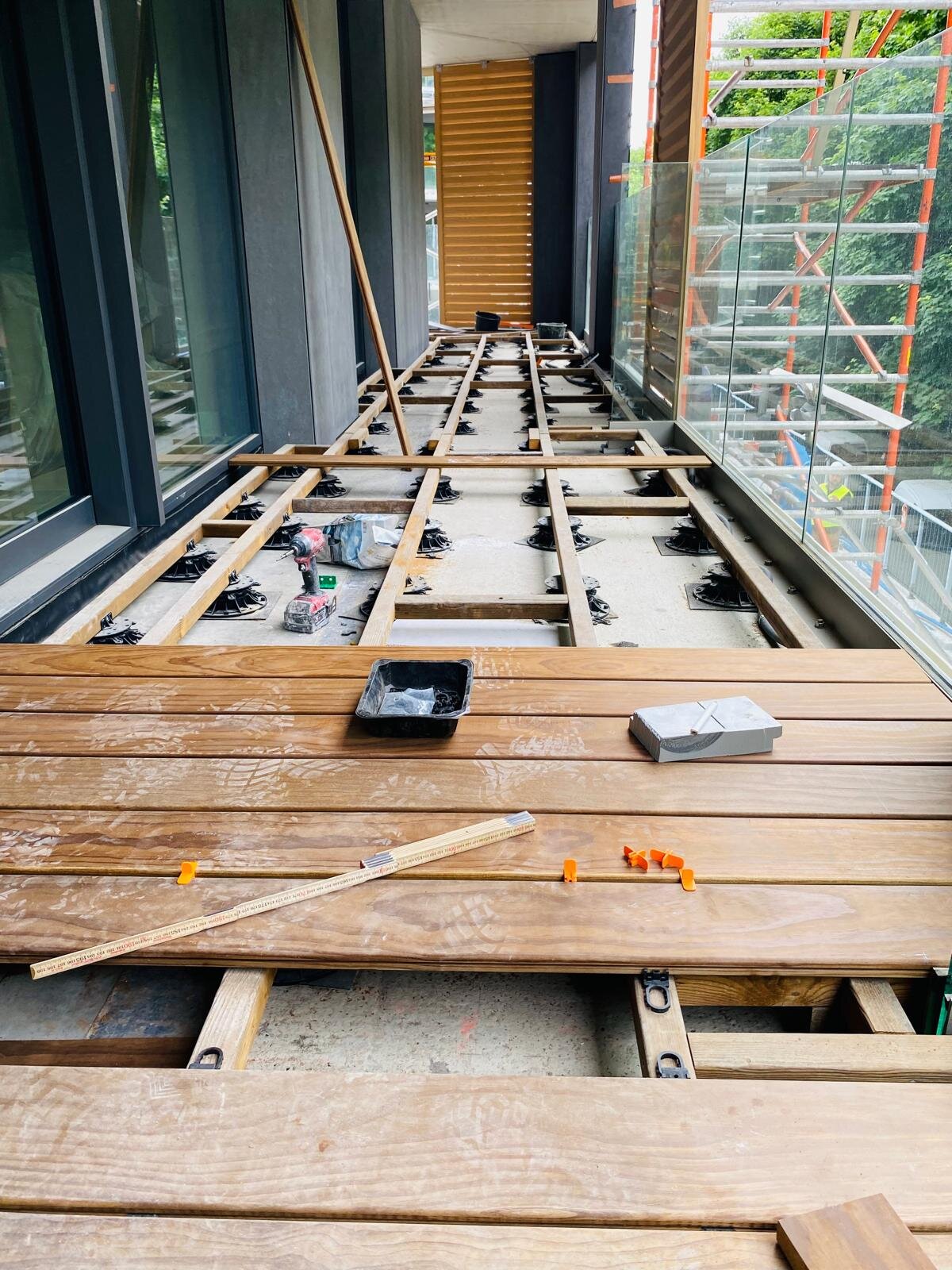 Balcony deck installation featuring hardwood decking boards laid over an adjustable pedestal substructure.