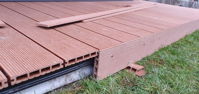 Hollow-core composite decking boards with fascia trim installed during outdoor deck construction.