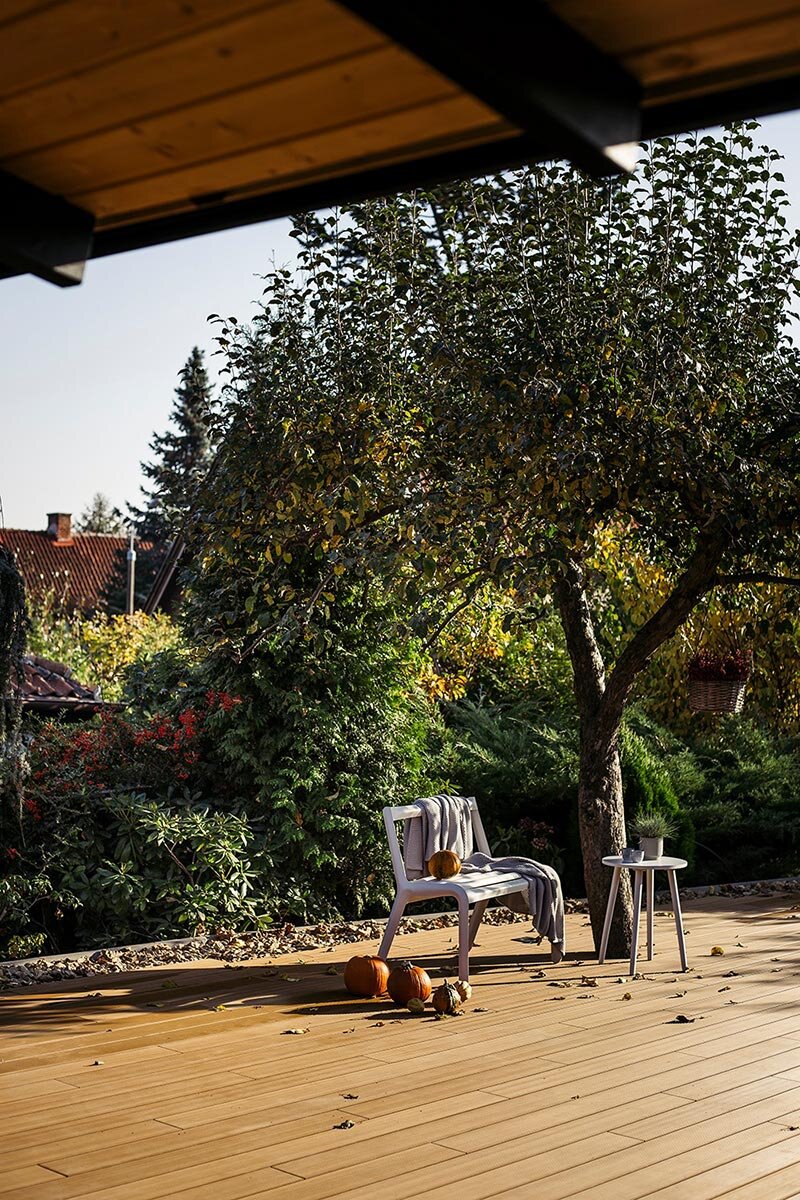 Cozy garden terrace featuring modern outdoor composite decking decorated with autumn pumpkins and garden seating.