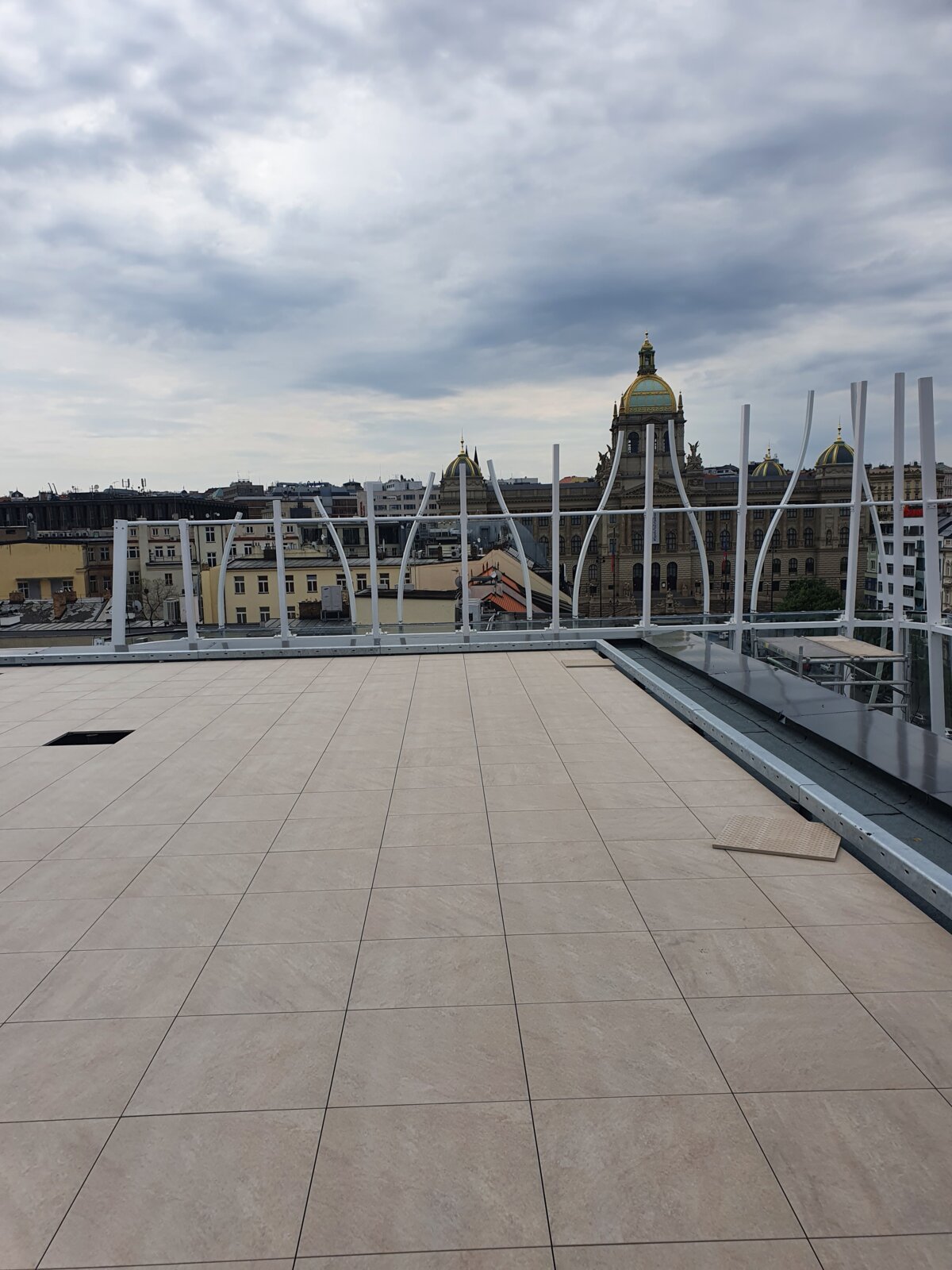 Rooftop terrace with installed outdoor porcelain paver tiles overlooking historic city buildings.