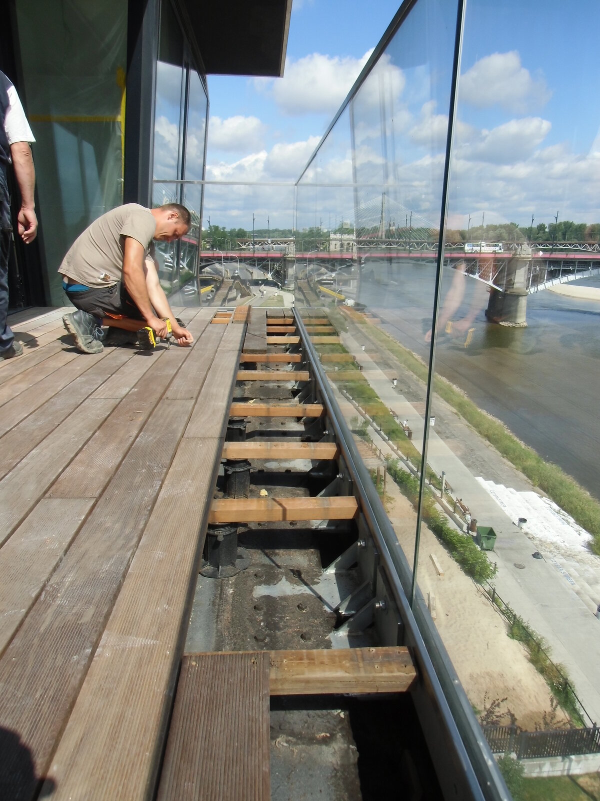 Contractor installing outdoor decking over adjustable pedestal supports on a balcony.