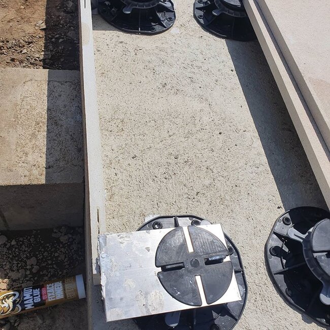 Adjustable pedestal paver support system installed on concrete base.