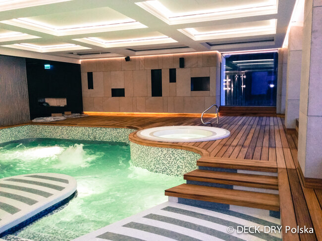 Raised wooden decking installed over indoor swimming pool using adjustable pedestals.
