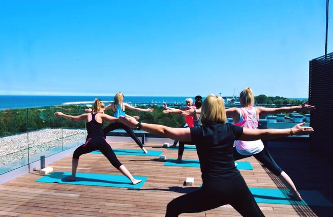 Rooftop deck built with adjustable pedestal support hosts an outdoor yoga class.