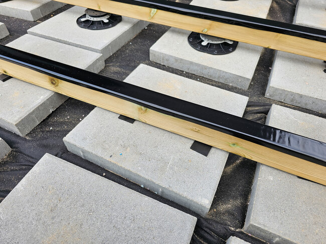 Adjustable pedestals and concrete paver foundations supporting wooden deck joists.