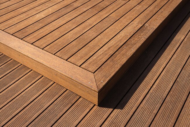 Close-up of a multi-level wooden deck featuring smooth planks bordered by grooved decking boards.
