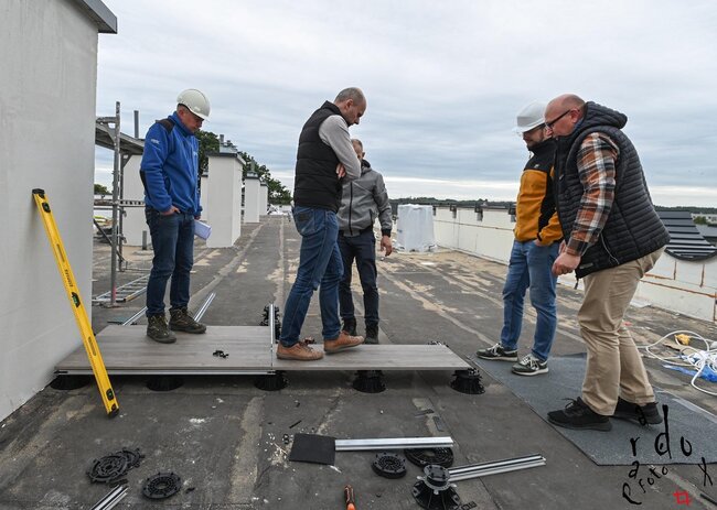Engineers inspecting raised deck tile installation on a rooftop terrace.