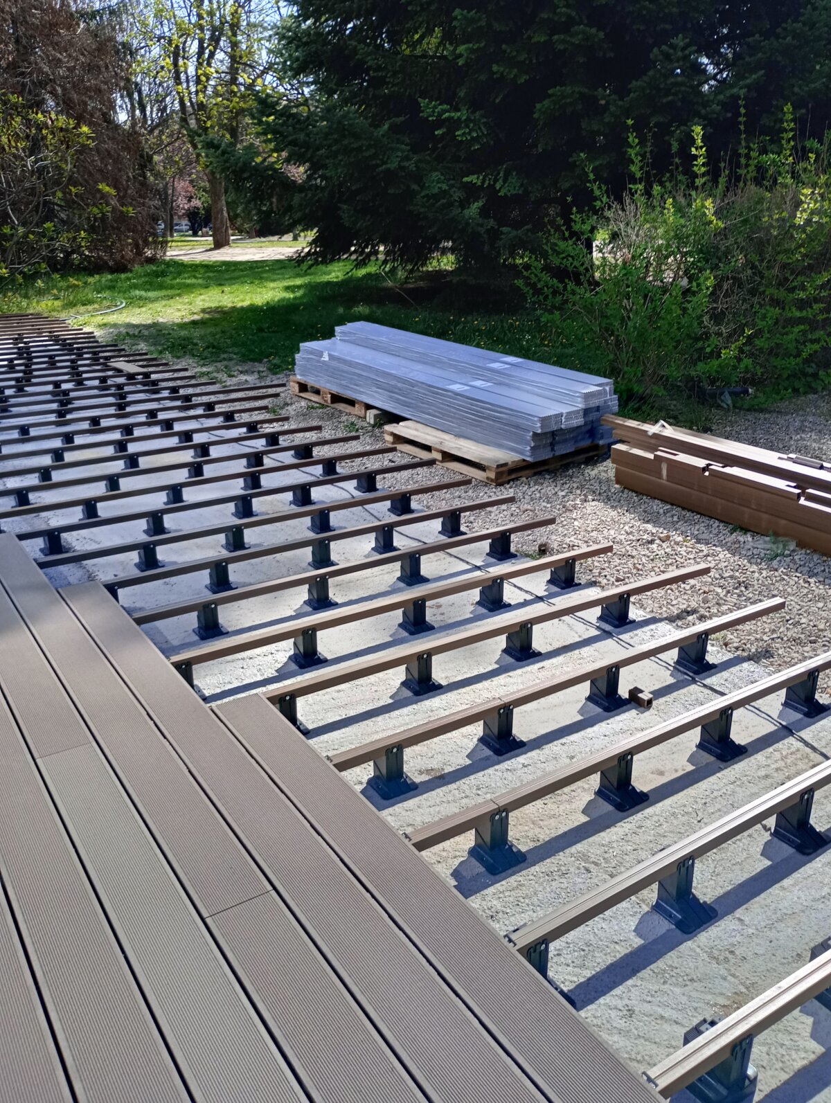 Composite decking boards being installed on aluminum joists supported by adjustable pedestals.
