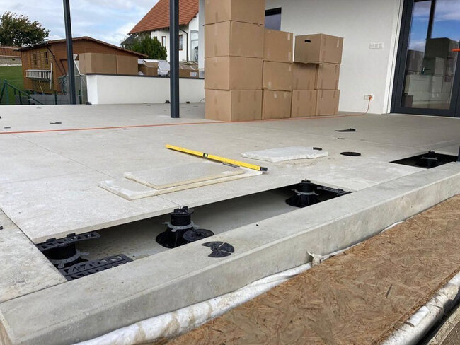 Raised terrace tile installation using adjustable pedestals on an outdoor patio.