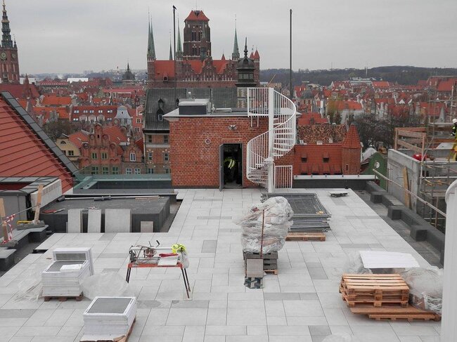 Rooftop terrace under construction featuring raised paver flooring on adjustable pedestals.