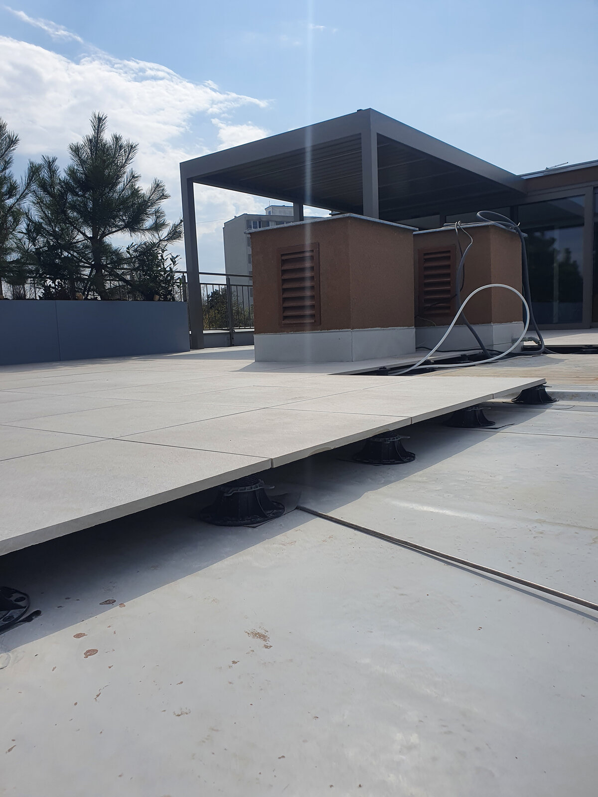 Adjustable pedestal system supporting raised outdoor patio tiles.