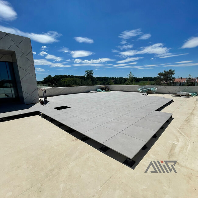 Elevated paver flooring system supported by black adjustable paving pedestals.