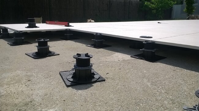 Raised patio terrace installation using adjustable pedestals to support large porcelain paving slabs.