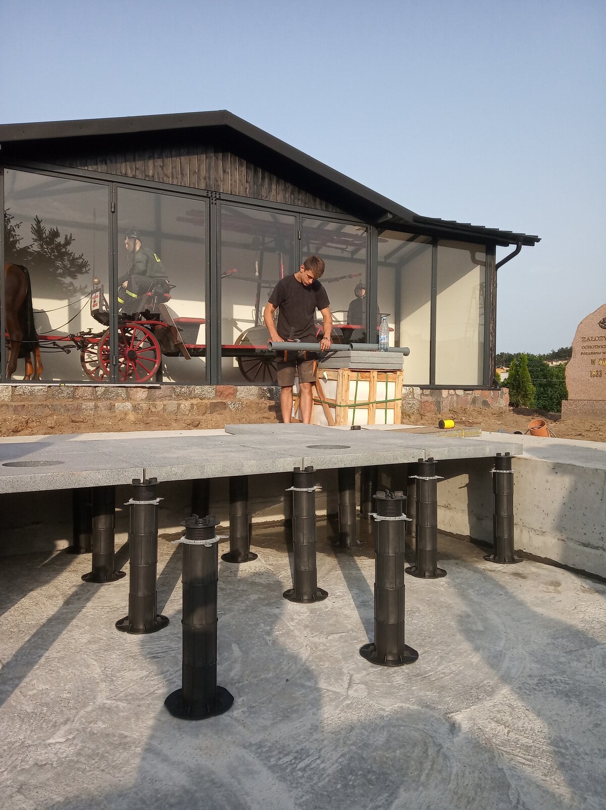 Installation of tall adjustable pedestals supporting stone pavers for an outdoor fountain raised floor system.