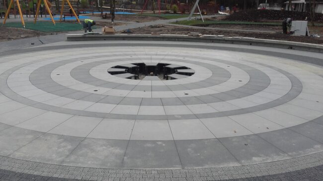 Circular raised paver floor installation around an outdoor dry deck fountain supported by adjustable pedestals.