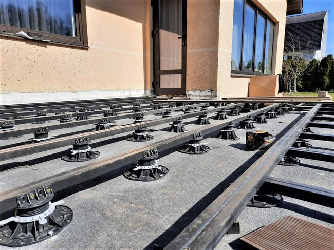 Adjustable deck pedestals supporting metal joist substructure for composite decking installation.