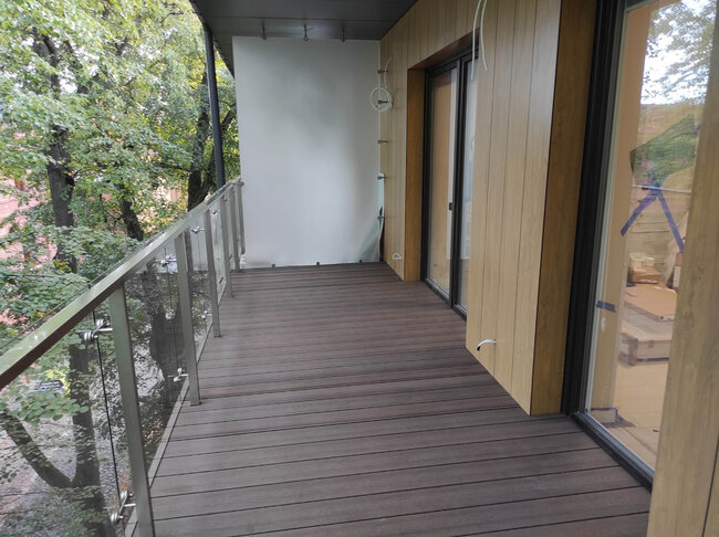Finished composite decking installed on a modern balcony using adjustable pedestals.
